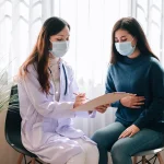 Doctor examining woman with stomach pain in hospital for acidity and digestive issues